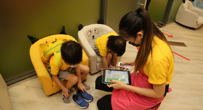 A landscape shot of a Sunway Little Sunshine homeroom teacher helping toddlers check-in the Oodlins app upon arrival