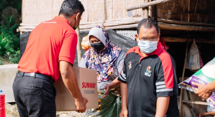 A medium full landscape shot of Sunway Lost World of Tambun general manager Nurul Nuzairi Mohd Azahari distributing groceries and spreading Raya Cheer to the Orang Asal community in Kampung Sg. Choh Perak
