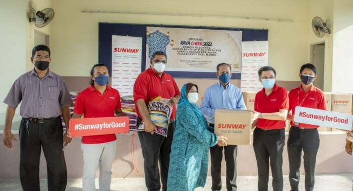 A full landscape shot of Sunway Construction senior manager of PR and Stakeholder Management Mohd Sofie bin Hassan, Sunway Hotel Georgetown Penang and Sunway Hotel Seberang Jaya general manager Prakash Kumaran, Sunway Property Penang general manager Fong Choon Fuoi and Sunway Carnival Mall associate director of Finance Lee Yau Chong alongside Batu Maung state assemblyman YB Dato’ Hj Abdul Halim Hussain and Qaryah chairman Haji Zainuddin distributing basic household items and groceries to B40 families in Penang through the #SunwayforGood Raya Cheer initiative at Surau Nur Hidayah, Kampung Jalan Tengah.