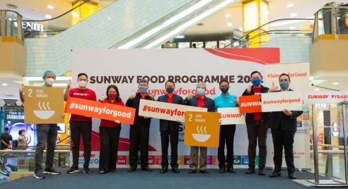 A full landscape shot of Sunway leaders and key stakeholders holding up #SunwayforGood and SDGs signs respectively during the launch of Sunway Meal Pack-a-Thon 2022.