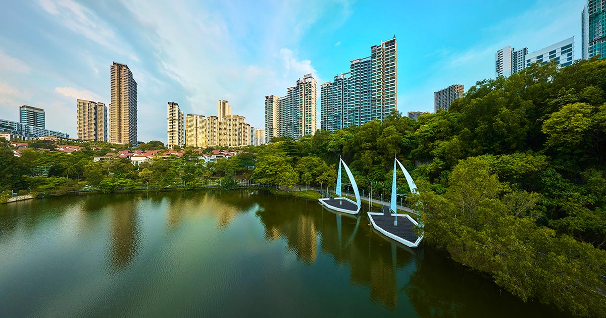 A panoramic view of Sunway South Quay lake, with two boats in the foreground and the Sunway City Kuala Lumpur skyline in the background