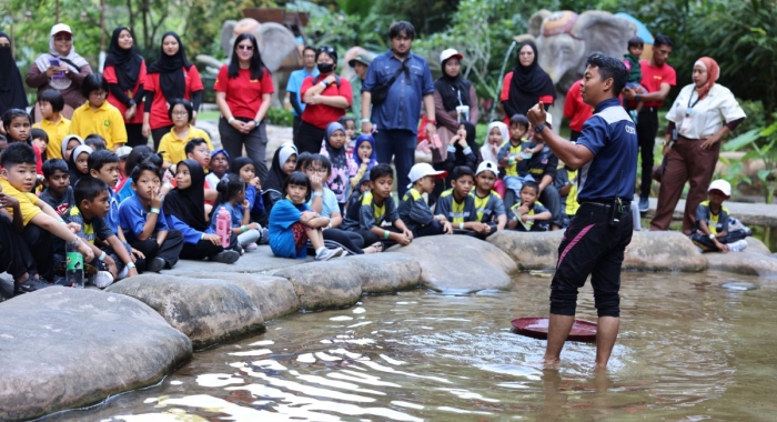 A Sunway Lost World Of Tambun staff giving an explanation to the children and staff from homes