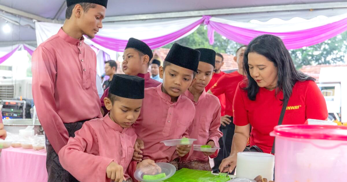 A mid shot of a Sunway staff serving children kuih during Ramadan.