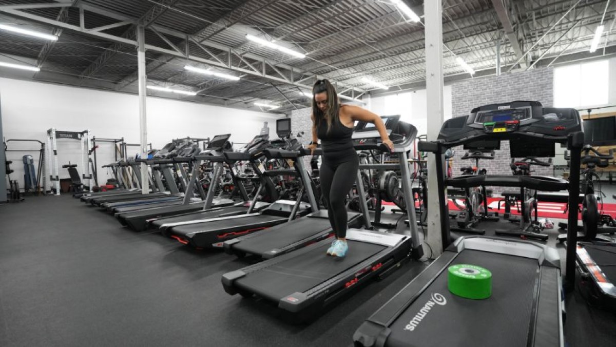 A lady walking backwards on the treadmill at a gym