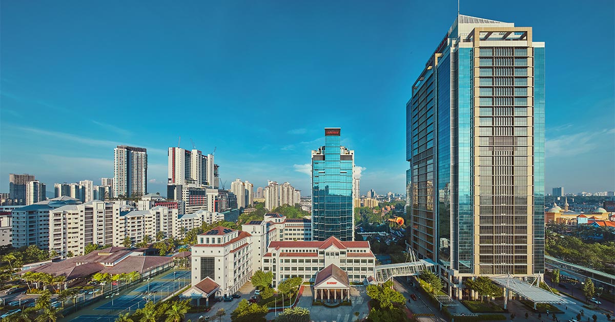 A centralised drone shot of Menara Sunway, Sunway Pinnacle and buildings of Sunway City Kuala Lumpur amidst a blue morning sky