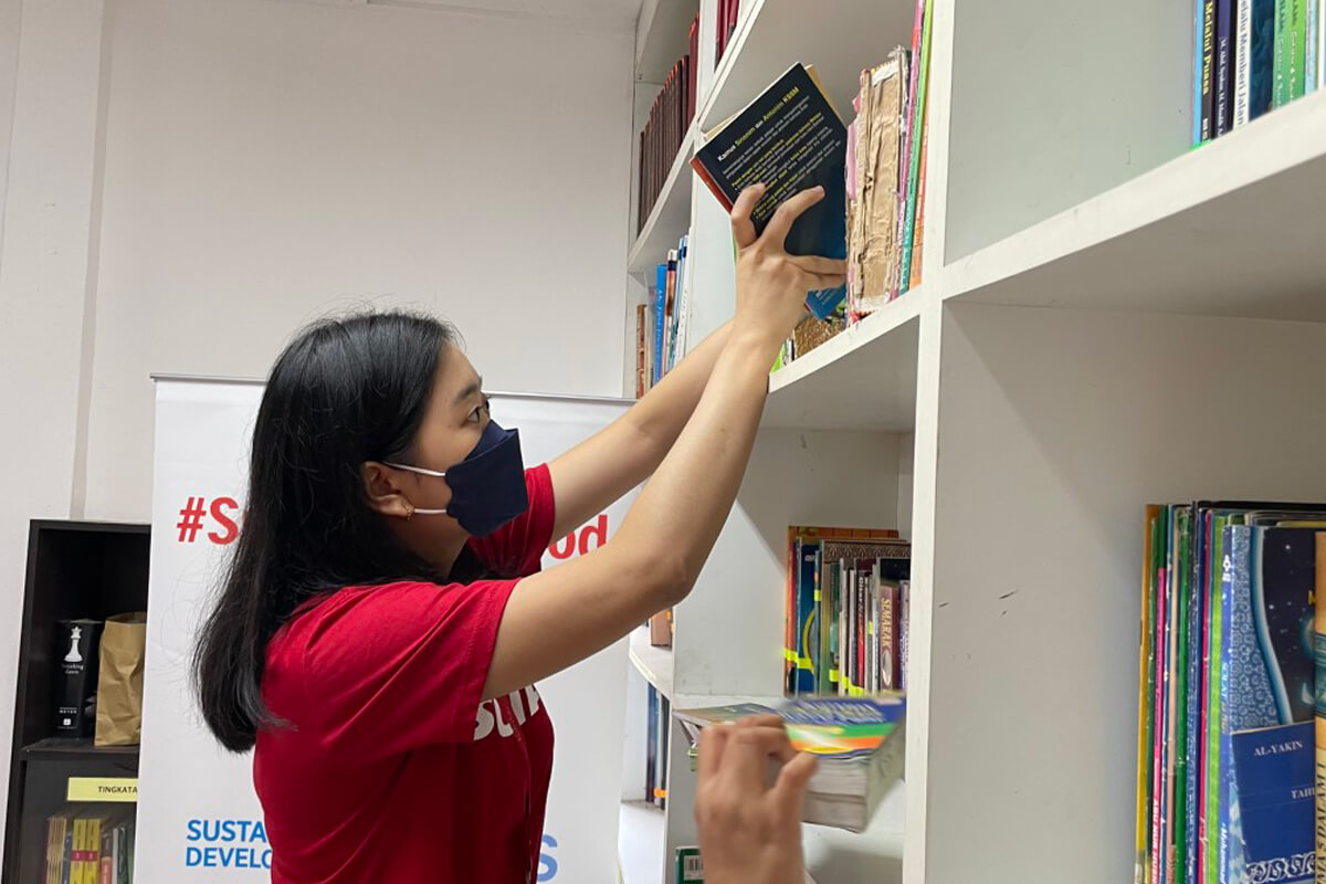 A female Sunway volunteer is arranging books at the Sunway READ library