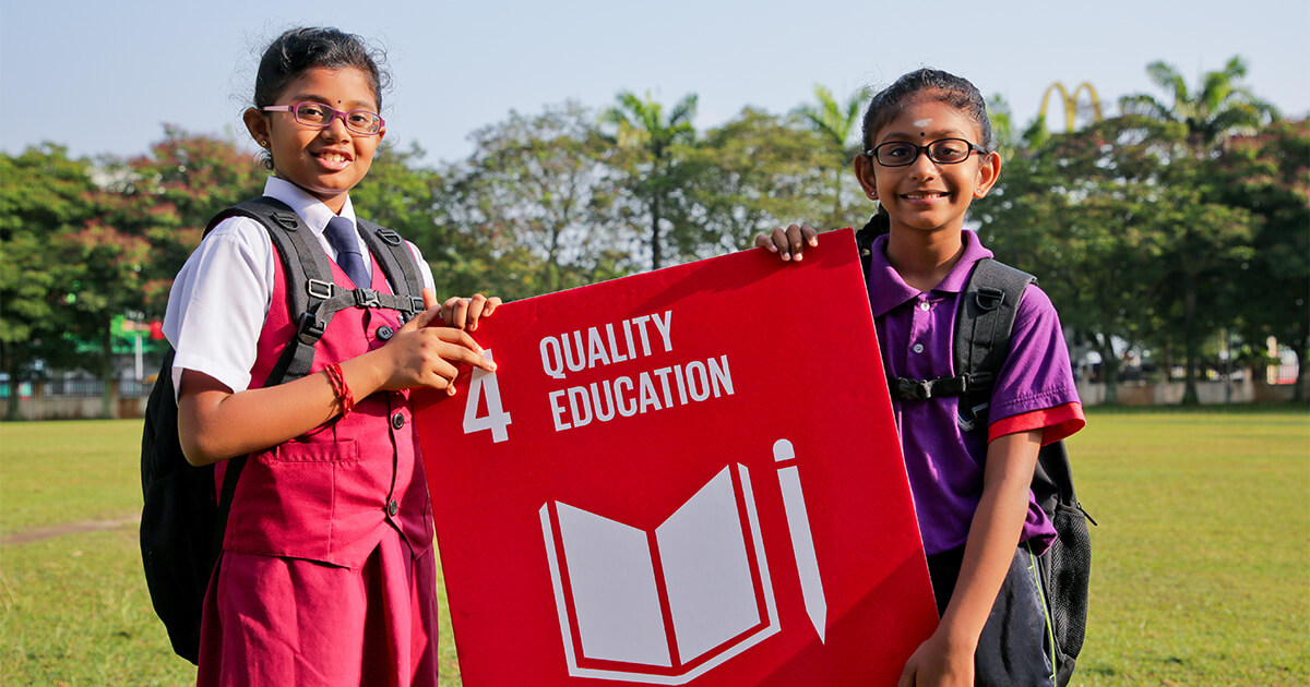 Two school children holding the “SDG 4: Quality Education” sign